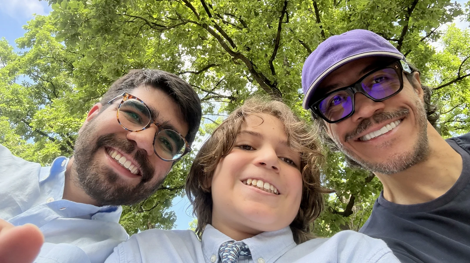 Family selfie beneath green trees